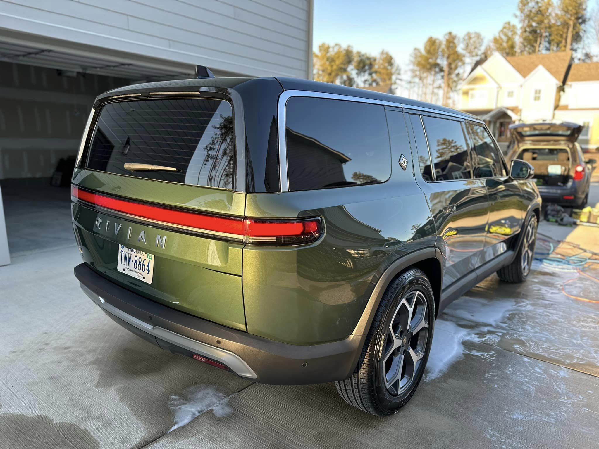 Rear quarter panel of a gleaming olive green Rivian