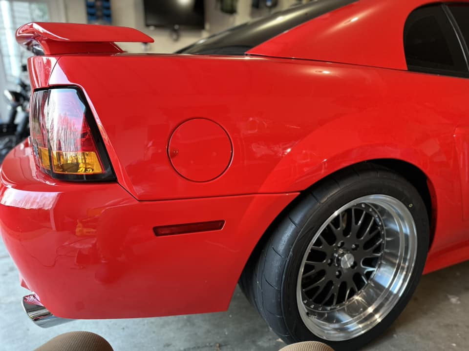 Closeup of the rear panel and spoiler on a fiery red Mustang SVT Cobra after a full paint restoration