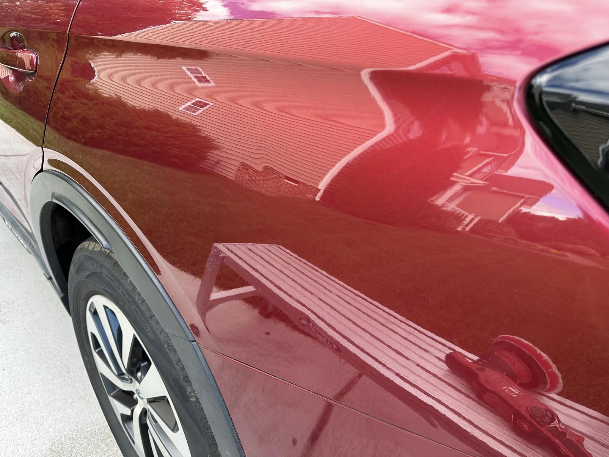 close up of a red car reflecting the surroundings after a paint correction service